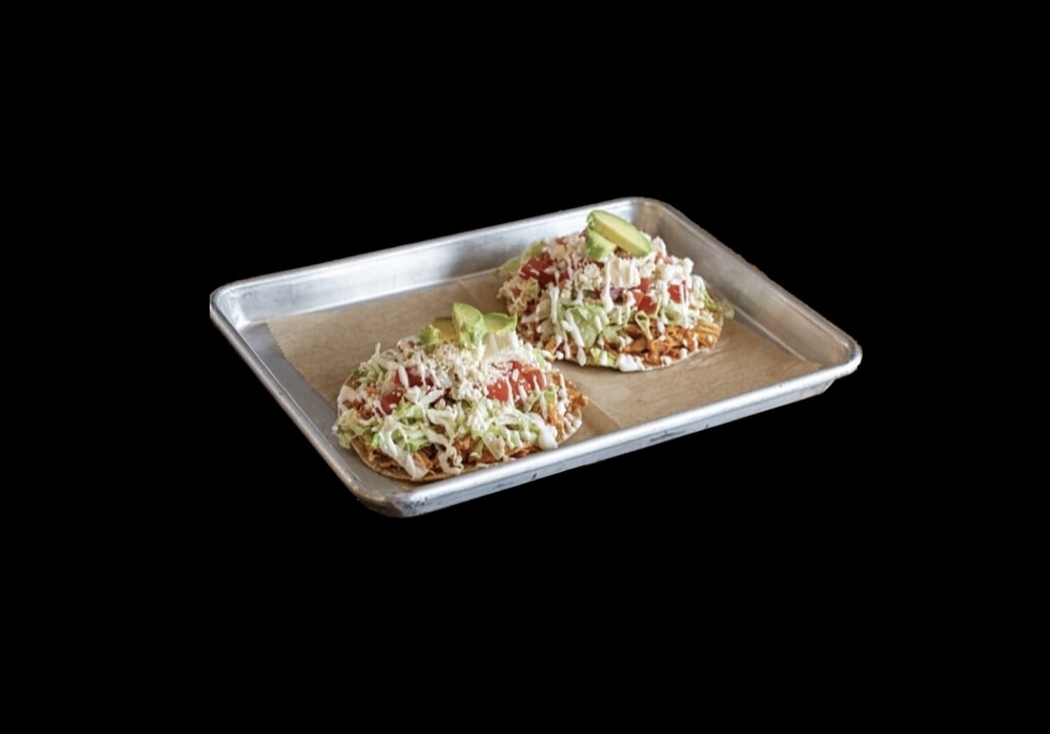 Flavor-packed Bean Tostada from Atwater Street Tacos, featuring a crispy tortilla topped with refried beans, lettuce, tomato, avocado, sour cream, diced onions, and crumbled queso fresco, epitomizing the richness of Mexican cuisine.