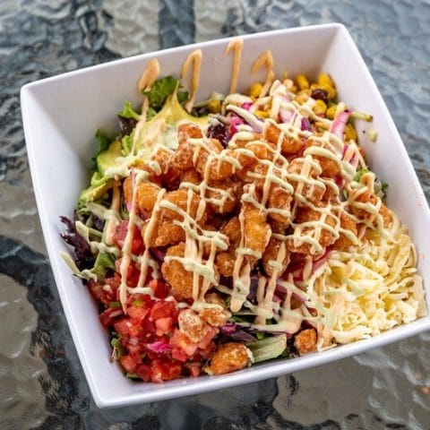 Image of Fried Shrimp Salad from Atwater Street Tacos, featuring Sriracha fried shrimp, red cabbage, spring mix, corn and black bean relish, pico de gallo, cheese, and avocado, drizzled with cilantro lime dressing. Available for takeout, delivery, or dine-in.