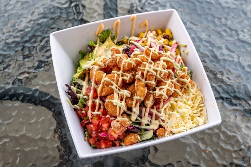 Image of Fried Shrimp Salad from Atwater Street Tacos, featuring Sriracha fried shrimp, red cabbage, spring mix, corn and black bean relish, pico de gallo, cheese, and avocado, drizzled with cilantro lime dressing. Available for takeout, delivery, or dine-in.