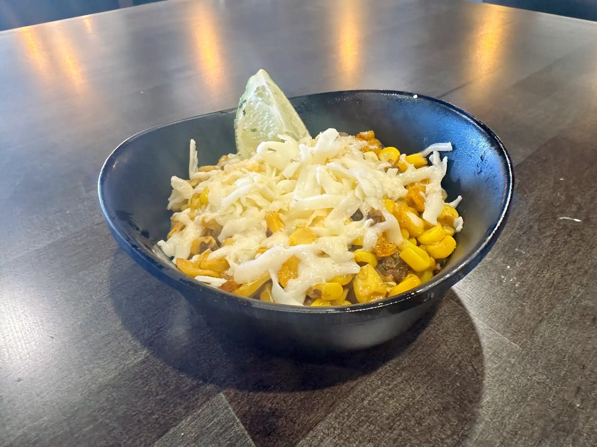 Bowl of Mexican street corn esquites topped with chorizo, cheese, and lime from Atwater Street Tacos.